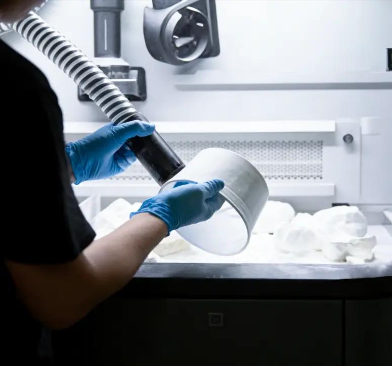 MJF post-processing: operator cleaning a printed nylon part at a processing station