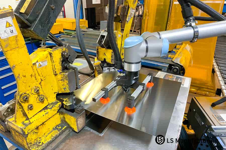 Orange robotic suction cups position ASTM 304 steel sheets for high-speed stamping of custom parts.
