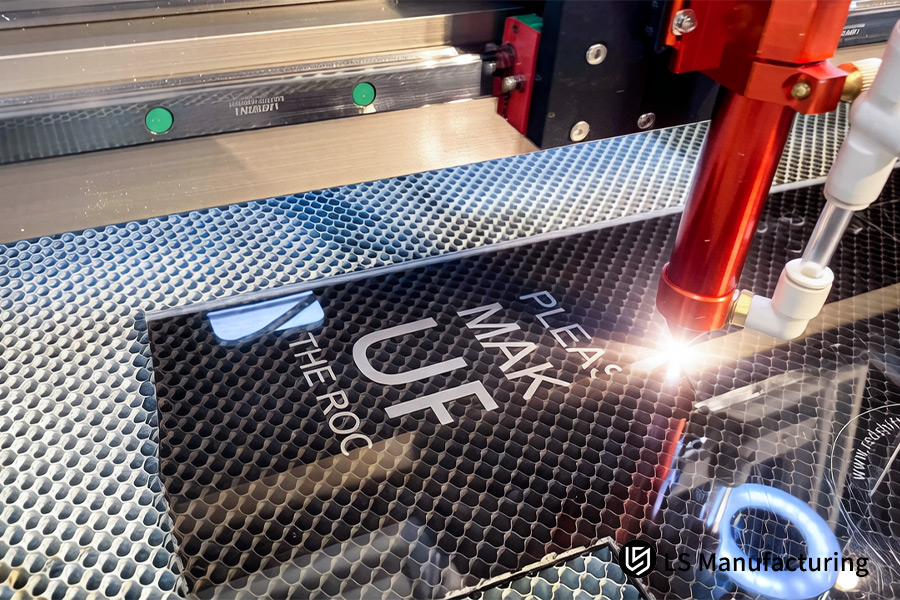 Laser cutting burns precise lettering on black acrylic signs for corporate exhibitions.